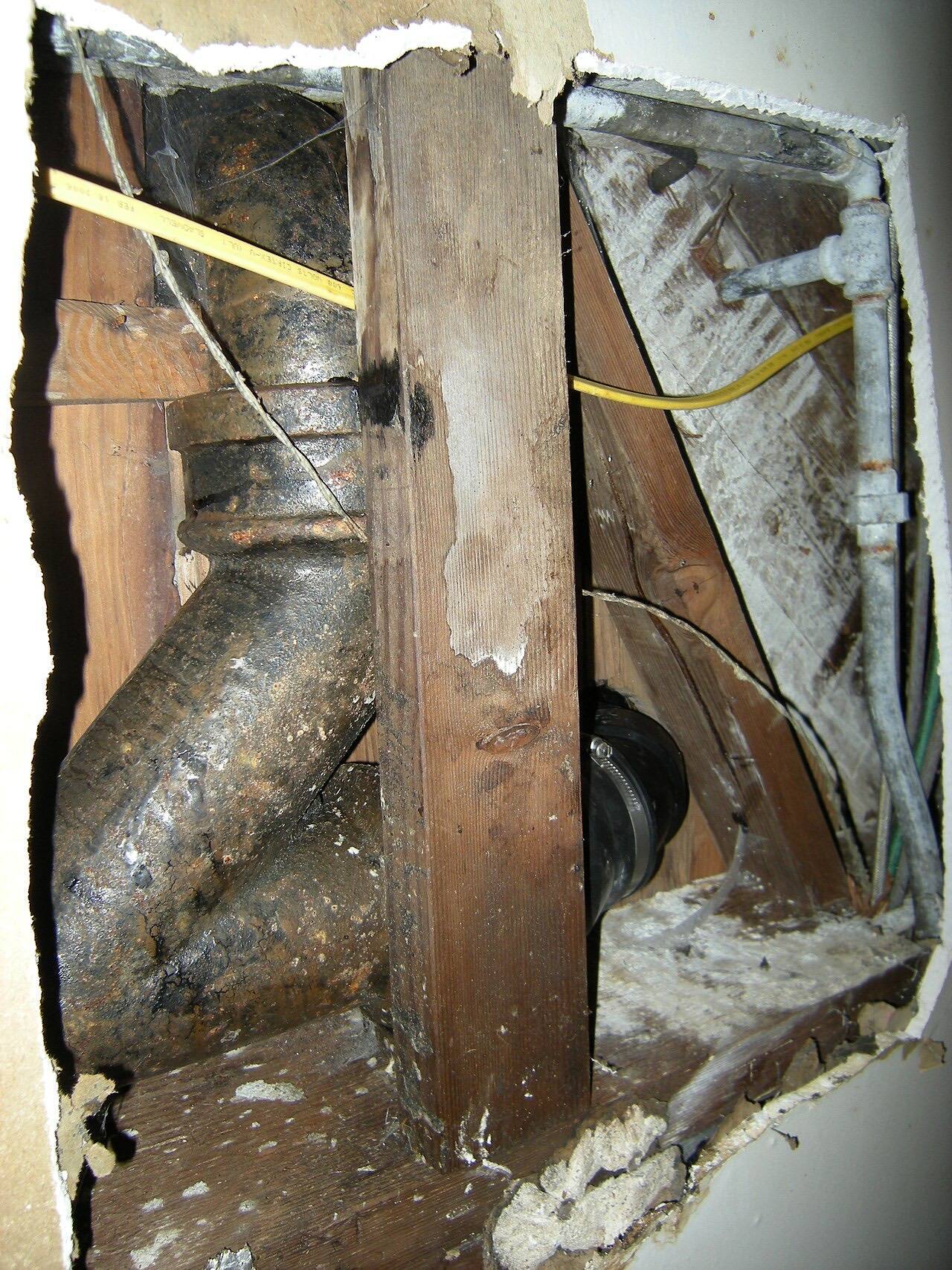 Four-inch cast-iron plumbing pipes (and at lower right center the three-inch down-pipe from a toilet) in the basement ceiling of a Seattle home.